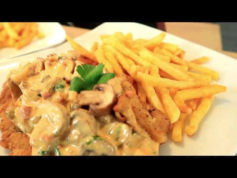 Knuspriges Schnitzel mit cremiger Pilzrahmsoße und Pommes frites